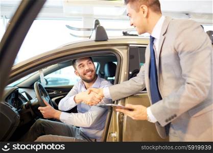 auto business, car sale, consumerism, gesture and people concept - happy man with car dealer making deal and shaking hands in auto show or salon