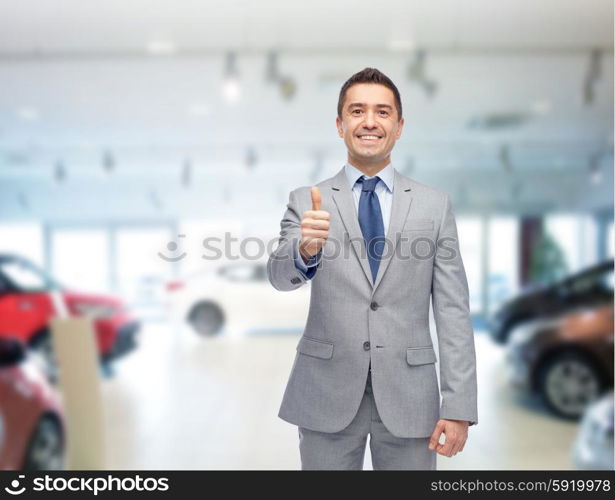 auto business, car sale, consumerism, gesture and people concept - happy man showing thumbs up over auto show or salon background