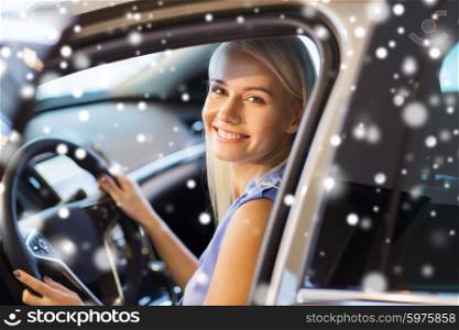 auto business, car sale, consumerism , transportation and people concept - happy woman sitting in or driving car over snow effect