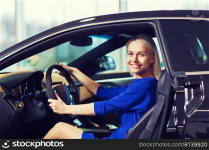 auto business, car sale, consumerism , transportation and people concept - happy woman sitting inside car in auto show or salon