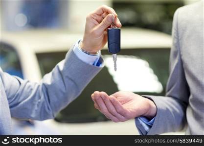 auto business, car sale, deal and people concept - close up of male hands with car key in auto show or salon