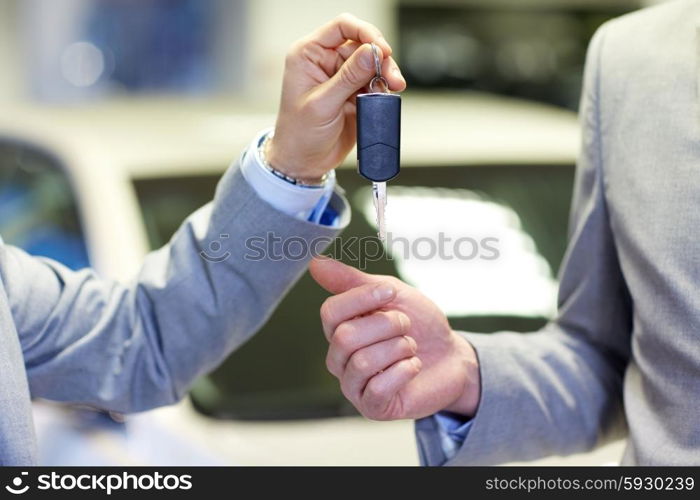 auto business, car sale, deal and people concept - close up of male hands with car key in auto show or salon