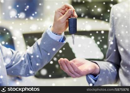 auto business, car sale, deal and people concept - close up of male hands with car key in auto show or salon over snow effect