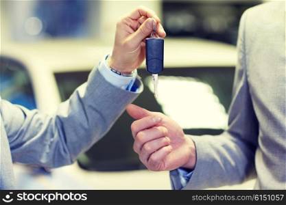 auto business, car sale, deal and people concept - close up of male hands with car key in auto show or salon