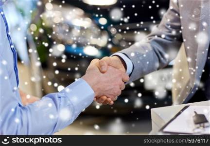 auto business, car sale, deal, gesture and people concept - close up of male handshake in auto show or salon over snow effect