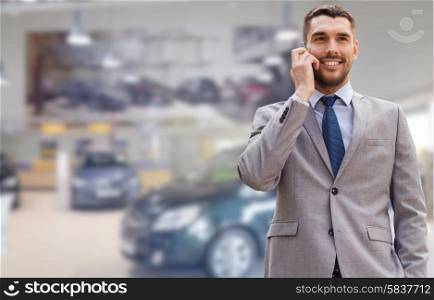 auto business, car sale, gesture and people concept - smiling businessman talking on smartphone over auto show background