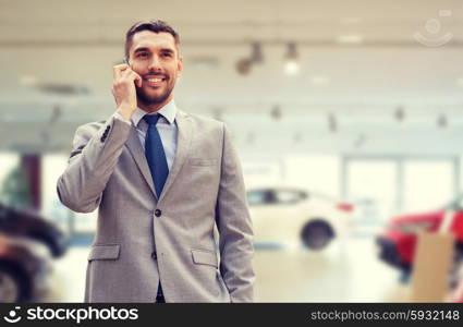 auto business, car sale, gesture and people concept - smiling businessman talking on smartphone over auto show background