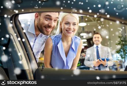 auto business, car sale, technology and people concept - happy couple looking inside car in auto show or salon over snow effect