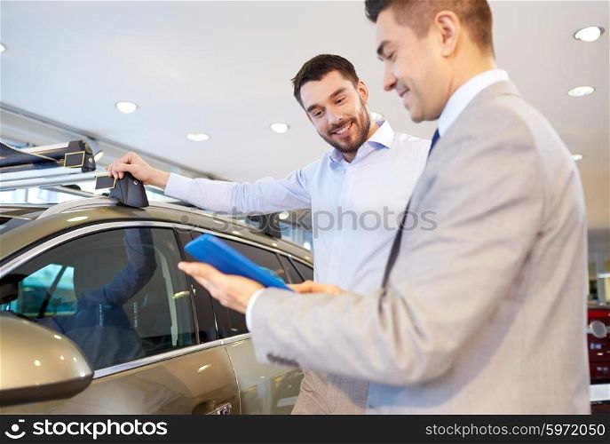 auto business, car sale, technology and people concept - happy man and car dealer with tablet pc computer in auto show or salon