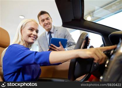 auto business, car sale, technology and people concept - happy woman and car dealer with tablet pc computer in auto show or salon