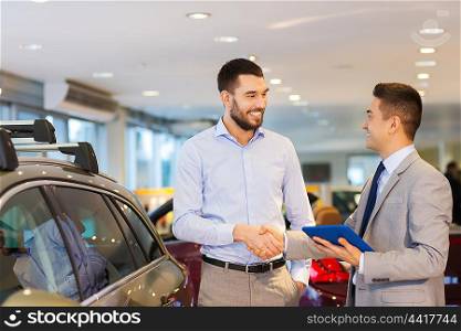 auto business, car sale, technology, gesture and people concept - happy man and car dealer with tablet pc computer shaking hands in auto show or salon