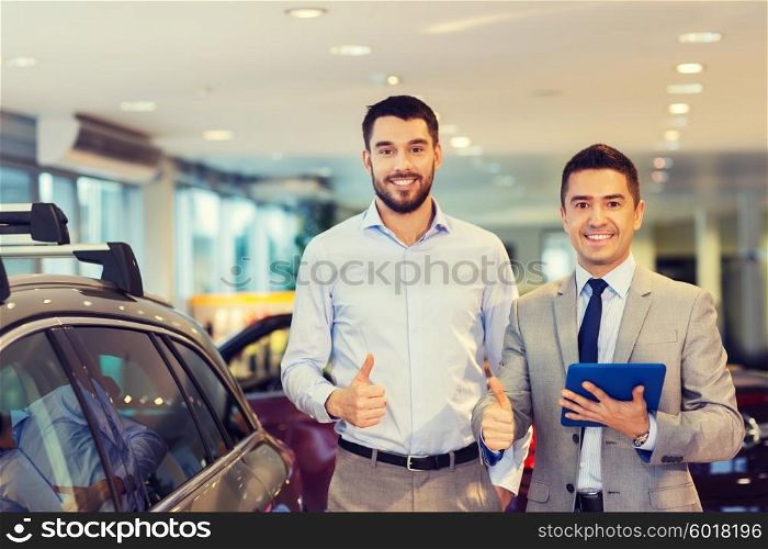 auto business, car sale, technology, gesture and people concept - happy man and car dealer with tablet pc computer showing thumbs up in auto show or salon
