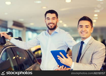 auto business, car sale, techology and people concept - happy man and car dealer with tablet pc computer in auto show or salon