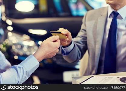 auto business, sale and people concept - close up of customer giving credit card to car dealer in auto show or salon