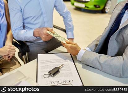 auto business, sale and people concept - close up of customers giving money to dealer and buying car in auto show or salon