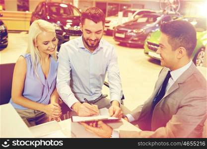 auto business, sale and people concept - happy couple with dealer buying car and signing documents in auto show or salon