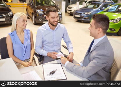 auto business, sale and people concept - happy couple with dealer buying car in auto show or salon