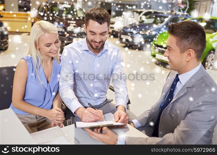 auto business, sale and people concept - happy couple with dealer buying car and signing documents in auto show or salon over snow effect