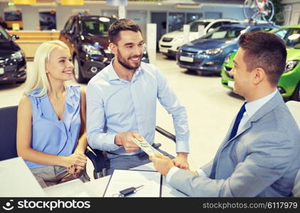 auto business, sale and people concept - happy couple with dealer buying car in auto show or salon