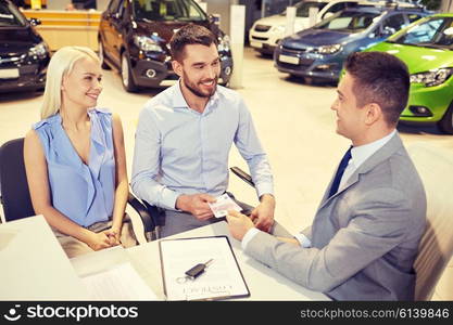 auto business, sale and people concept - happy couple with dealer buying car in auto show or salon