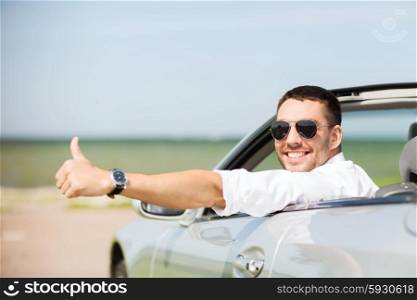 auto business, transport, leisure and people concept - happy man driving cabriolet car and showing thumbs up