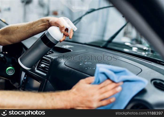 Auto detailing of car interior on carwash service. Worker in gloves cleaning salon with polishing spray