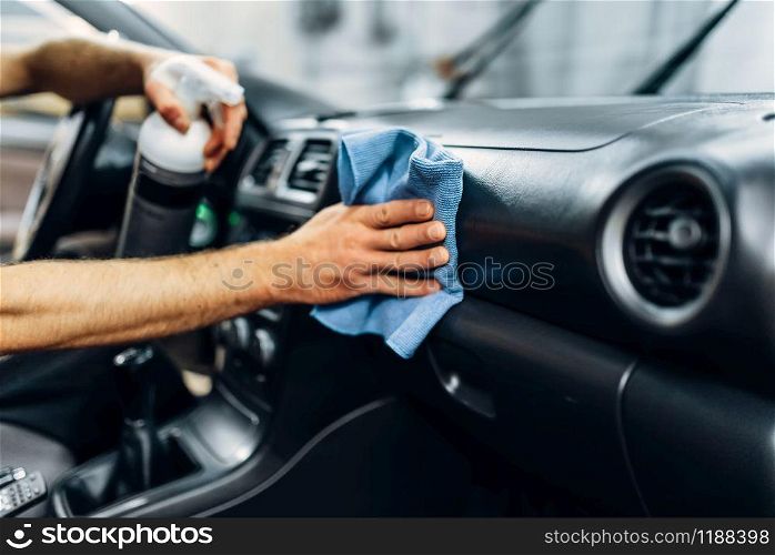 Auto detailing of car interior on carwash service. Worker in gloves cleaning salon with polishing spray. Detailing, cleaning salon with polishing spray