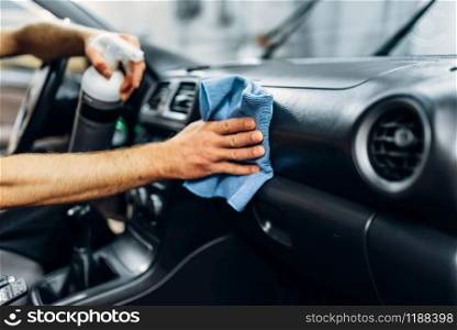 Auto detailing of car interior on carwash service. Worker in gloves cleaning salon with polishing spray. Detailing, cleaning salon with polishing spray