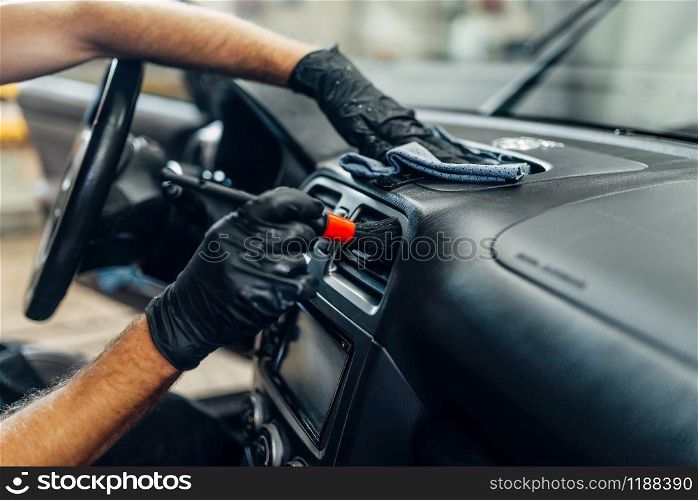 Auto detailing of car interior on carwash service. Worker in gloves cleans salon with brush. Auto detailing of car interior on carwash service