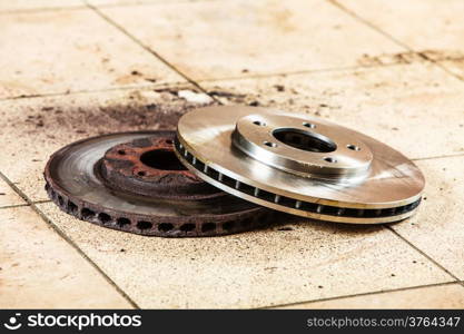 Auto in service. New and old front brake disks for modern car lying on floor in mechanic garage car service.