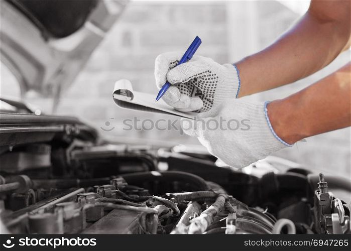 Auto mechanic checking car engine at the garage.. Auto mechanic checking car engine at the garage