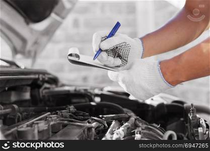 Auto mechanic checking car engine at the garage.. Auto mechanic checking car engine at the garage