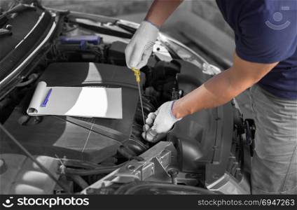 Auto mechanic checking the oil level in car engine.. Auto mechanic checking the oil level in car engine