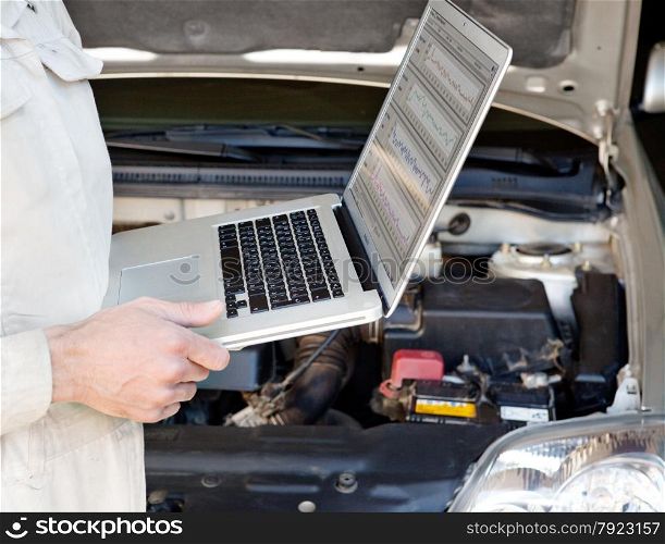 auto mechanic checks the car using a laptop