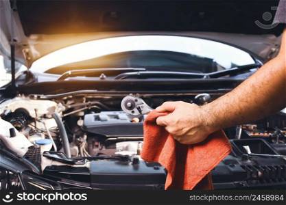 Auto mechanic hand holding wrench and red cloth to repair car with car engine background