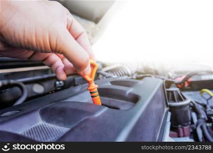 Auto mechanic hand is pulling the oil dipstick for checking lube level in the auto repair garage with copy space