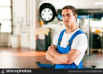 Auto mechanic standing in his workshop in front of a car on a hoist