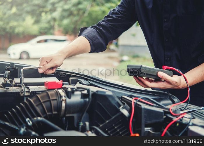 Auto mechanic working in garage Technician Hands of car mechanic working in auto repair Service and Maintenance check car battery.