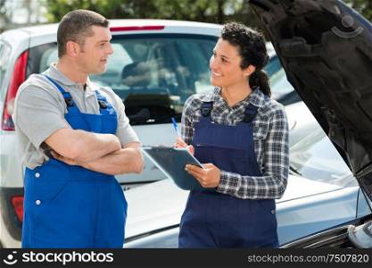 auto mechanics discussing something outdoors