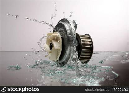 Auto parts, engine cooling pump in spurts of water on a light gradient background
