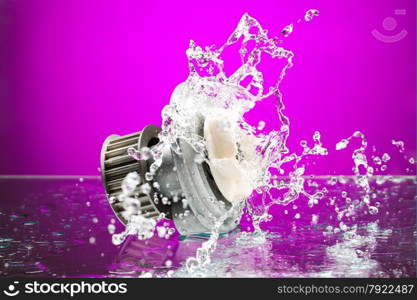 Auto parts, engine cooling pump in spurts of water on purple gradient background