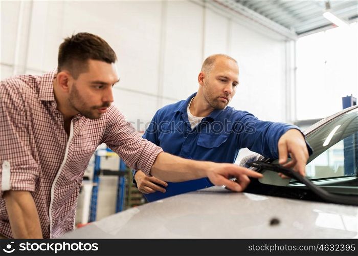 auto service, repair, maintenance and people concept - mechanic checking windshield wiper and man or owner at car shop