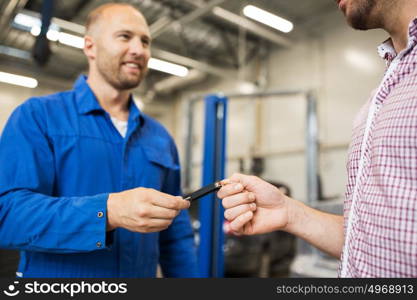 auto service, repair, maintenance and people concept - mechanic giving car key to man or owner at workshop. auto mechanic giving car key to man at workshop