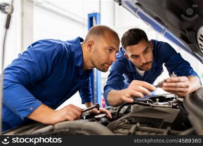 auto service, repair, maintenance and people concept - mechanic men with wrench repairing car at workshop