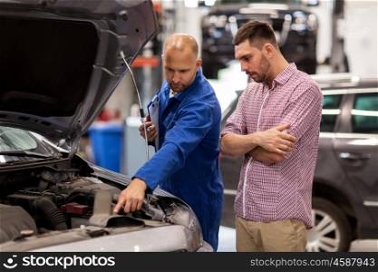 auto service, repair, maintenance and people concept - mechanic with clipboard and man or owner looking at broken car engine at shop
