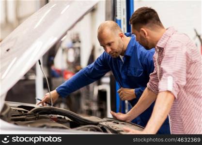auto service, repair, maintenance and people concept - mechanic with clipboard and man or owner looking at broken car at shop