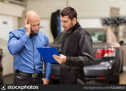 auto service, repair, maintenance and people concept - mechanic with clipboard and customer or car owner at workshop. auto mechanic and customer at car shop