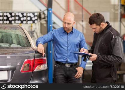 auto service, repair, maintenance and people concept - mechanic with clipboard and customer or car owner looking at taillight at workshop. mechanic and customer looking at car taillight