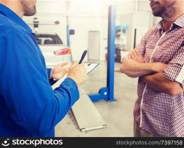 auto service, repair, maintenance and people concept - mechanic with clipboard and man or owner looking at broken car at shop. auto mechanic with clipboard and man at car shop
