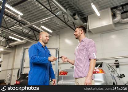 auto service, repair, maintenance and people concept - mechanic with clipboard giving key to happy smiling man or owner at car shop